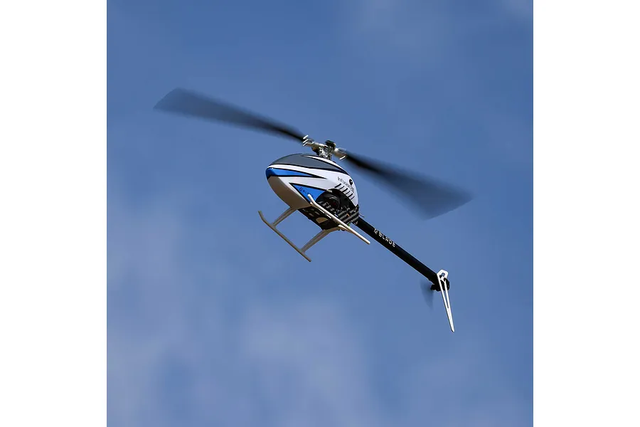 Blade InFusion 210 RC helicopter in flight against a clear blue sky, showing its white, blue, and black color scheme with spinning rotor blades.