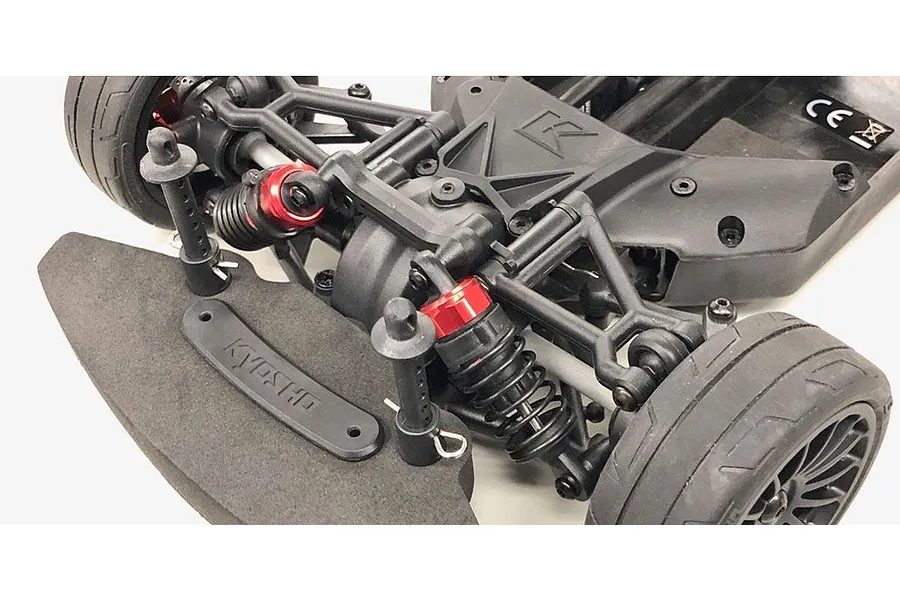 Close-up of the front suspension and shock absorbers installed on a Kyosho RC car chassis.