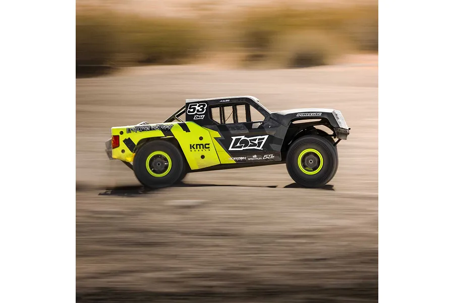 Action shot of a black and yellow Losi RC short course truck driving fast across a dirt track, creating a motion blur effect.