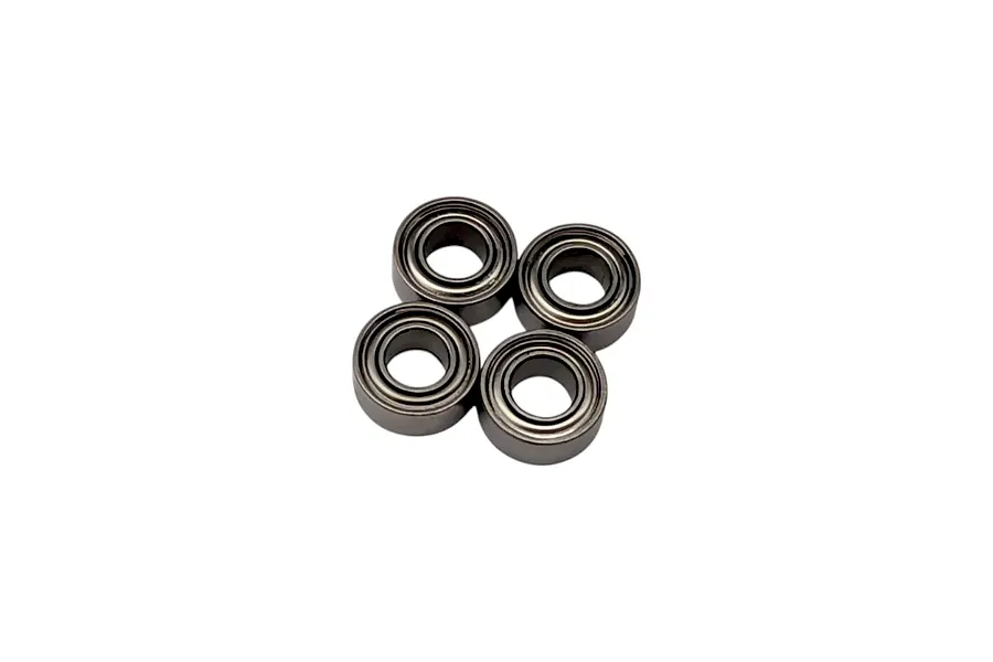 Four small metal shielded ball bearings grouped together on a plain white studio background.