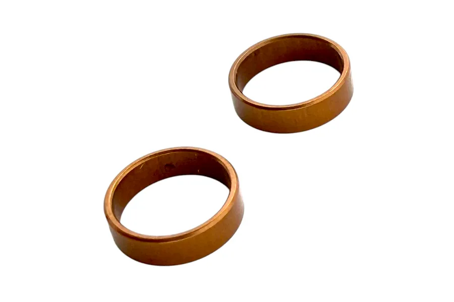 Two copper-coloured metal crush washers displayed against a clean white background.