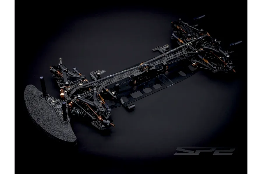 RC Maker SP2 EP 1/10 scale electric touring car chassis kit viewed from an elevated angle against a dark background.