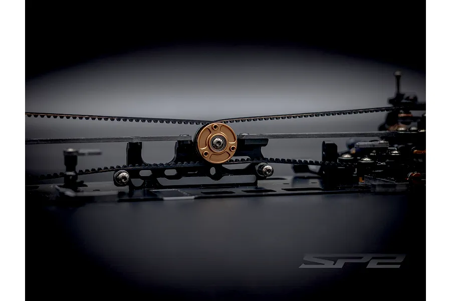 Close-up of the internal chassis belt drive and central bronze pulley of the RC Maker SP2 touring car kit.