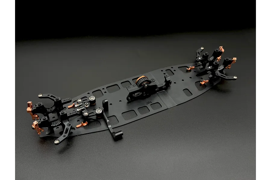 An assembled black and bronze aluminium RC car chassis with various mounted components against a dark background.