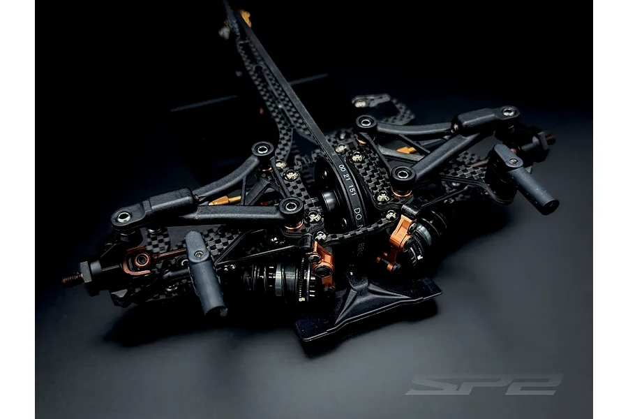 Close-up studio shot of the front suspension and chassis assembly of an RC Maker SP2 EP touring car kit.