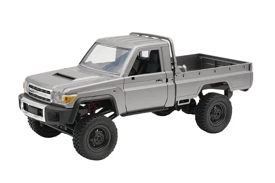 Studio product shot of a silver MN Model Toyota LC79 Pro RC rock crawler electric truck on a white background.