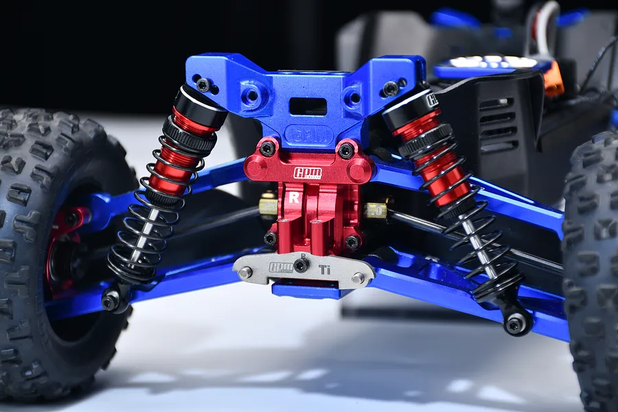 GPM titanium rear suspension pin brace installed on an RC car rear assembly with blue and red anodized aluminum parts.