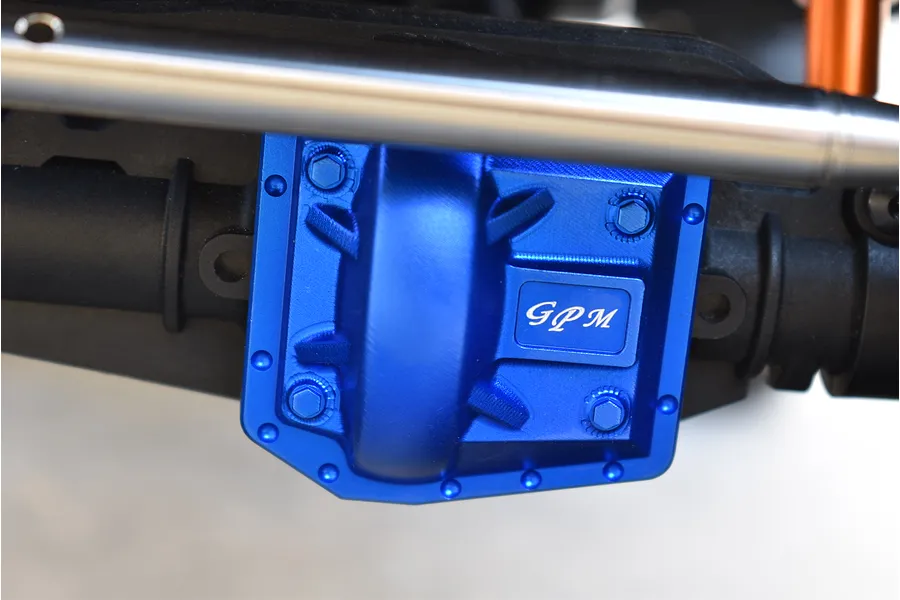 Blue anodized aluminum GPM gearbox cover installed on an RC vehicle axle, featuring hex hardware and logo branding.