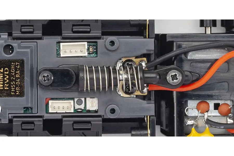 Close-up top view of the MR-04 chassis layout showing electronic components, spring damper, and wiring.
