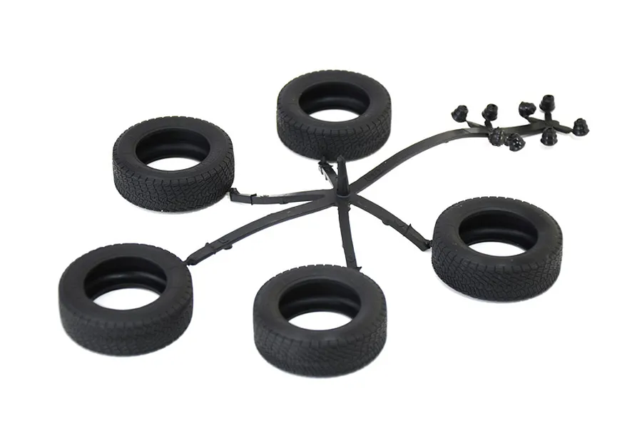 Five black model car rubber tires and small parts on a sprue against a plain white background.