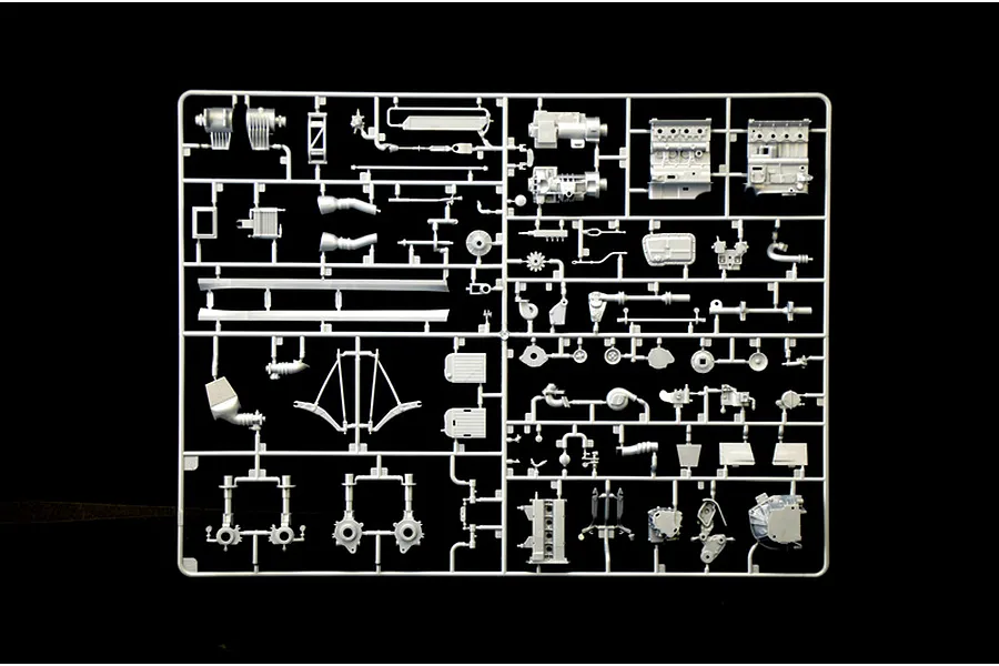 Grey plastic model kit parts sprue containing engine blocks and mechanical components on a black background.