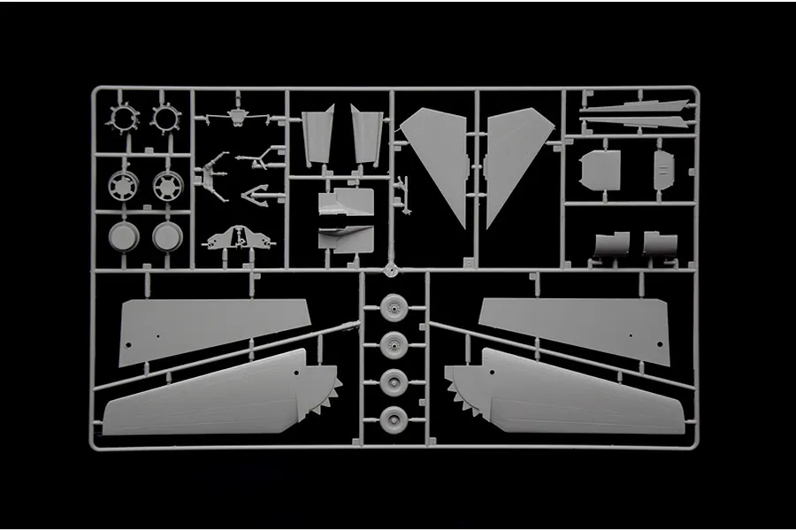 Grey plastic model kit sprue showing wings, wheels, and aircraft parts against a black background.