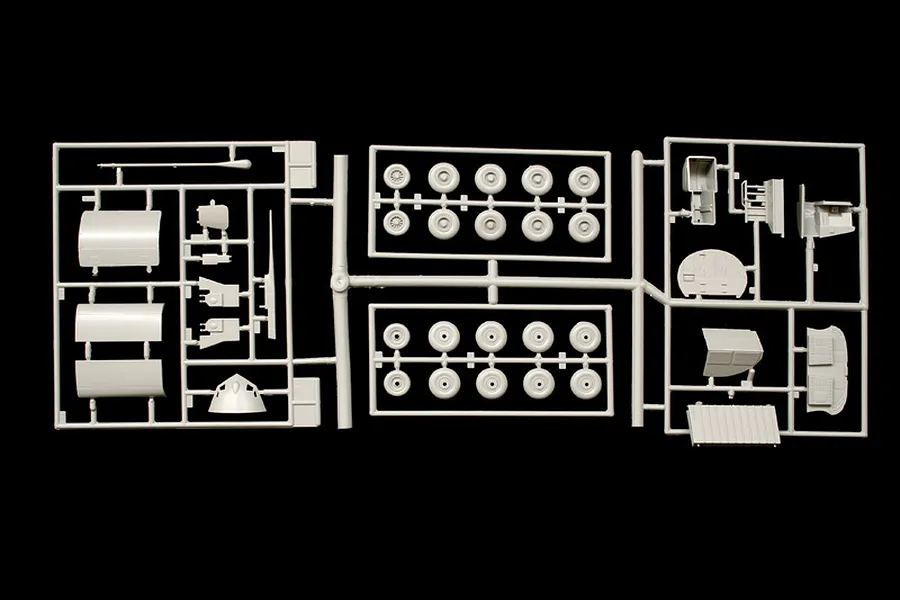 Grey plastic model kit sprues showing various parts and multiple wheels on a black background.