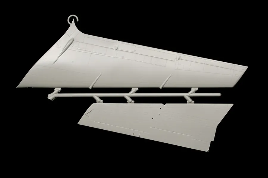 Grey molded plastic model kit parts sprue showing aircraft vertical stabilizer and rudder components against a black background.
