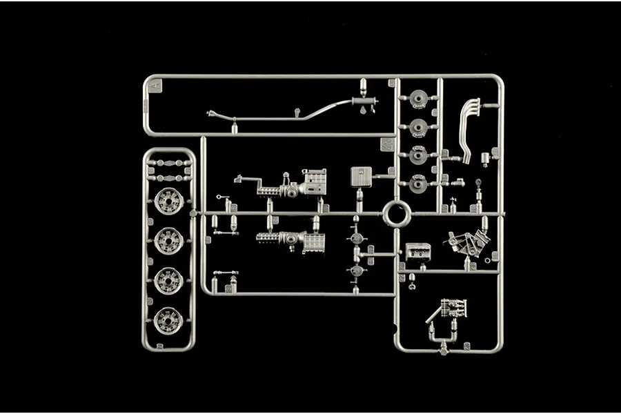 Grey plastic model kit parts sprue containing engine and wheel components on a black background.