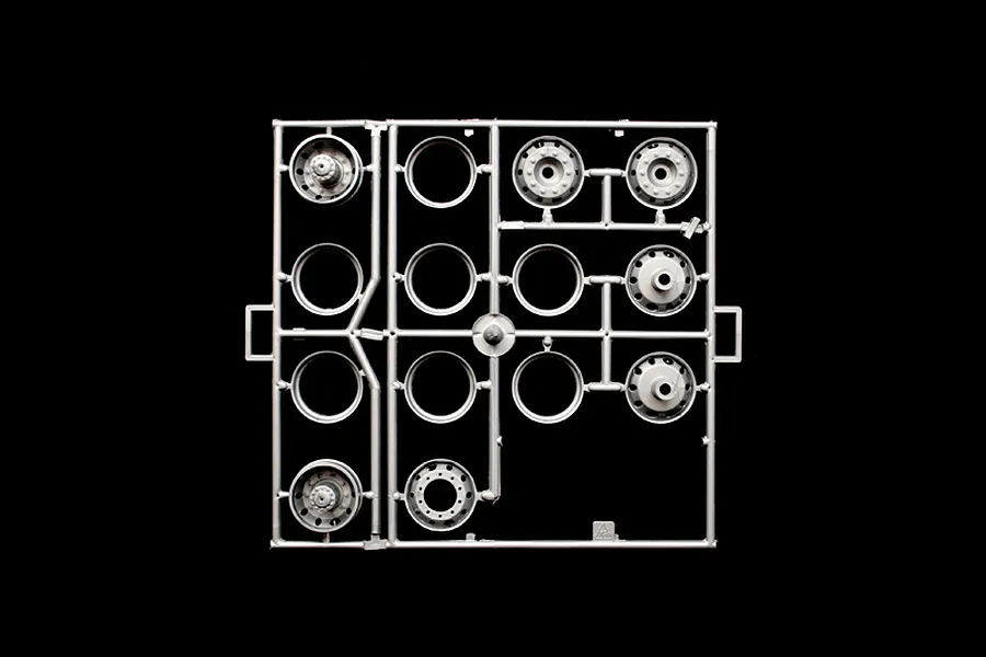 Grey plastic model parts sprue containing truck wheel rims and hub components against a black background.