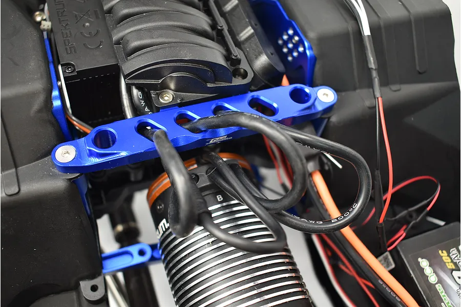 GPM blue aluminium front chassis brace installed on an RC vehicle chassis near the motor and electronics.