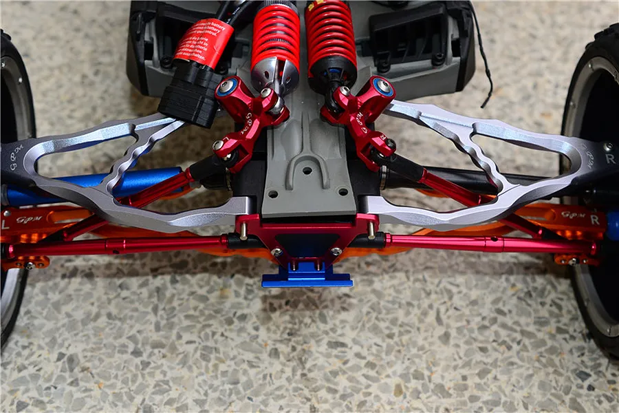 Close-up view of an RC car suspension featuring red aluminium turnbuckles and upgraded linkages mounted on a chassis.