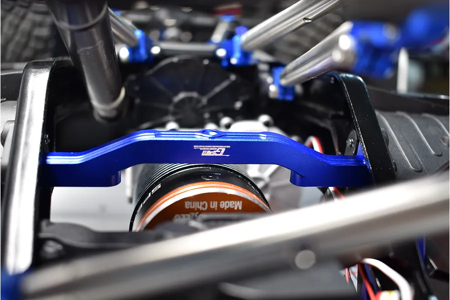 GPM blue aluminium front lower chassis brace installed on an RC vehicle chassis near the motor.