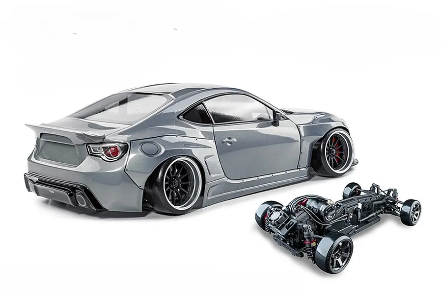 MST 86RB RC drift car in metal grey with widebody kit shown alongside its assembled chassis on a white background.