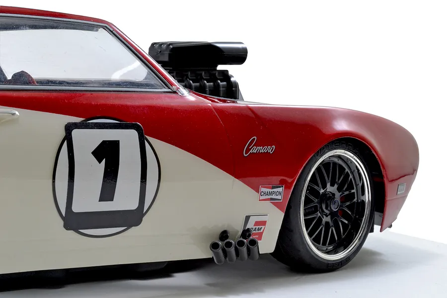 Close-up of a red and white RC car body featuring a black blower scoop protruding from the hood.