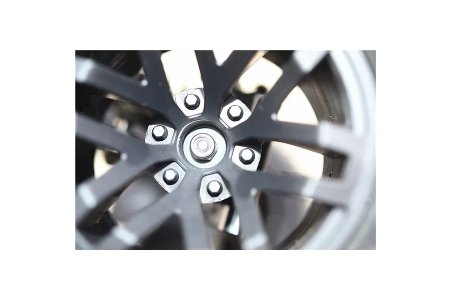 Close-up of a black RC wheel mounted with a wheel nut and internal hex components installed on a vehicle.