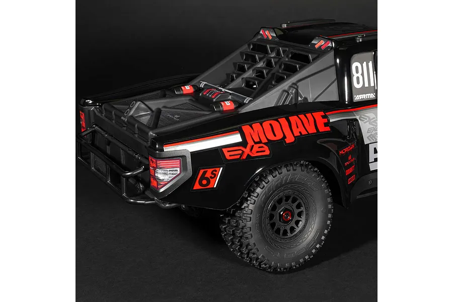 Close-up rear quarter view of the ARRMA MOJAVE 6S EXB RC desert truck in black, highlighting rear body details, roll cage, and textured tire.