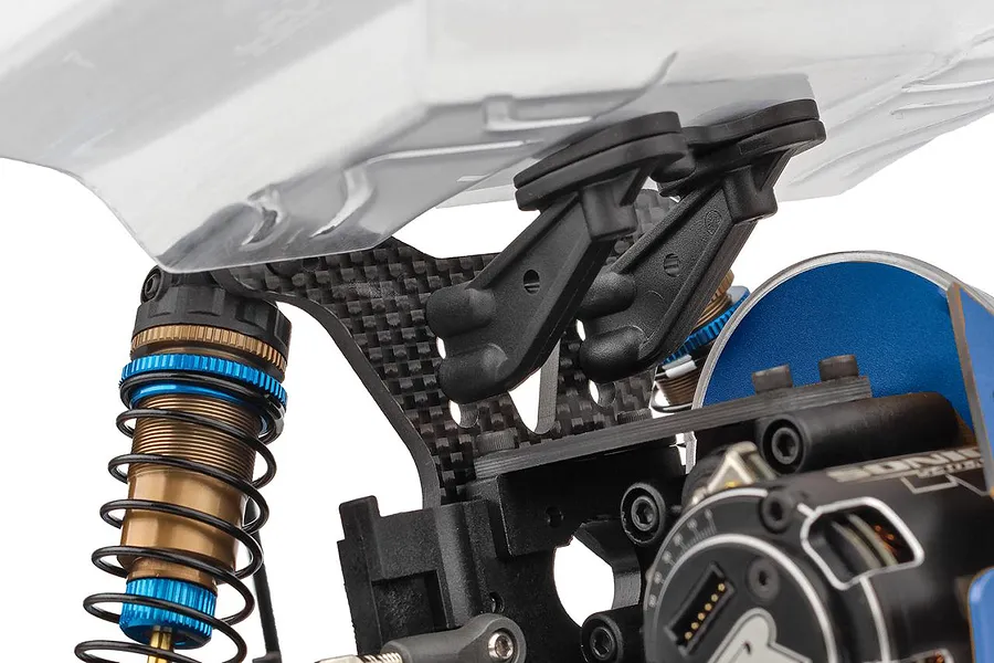 Close-up of the carbon fiber rear shock tower, aluminum shock absorber with blue accents, and body mounts on an RC car.