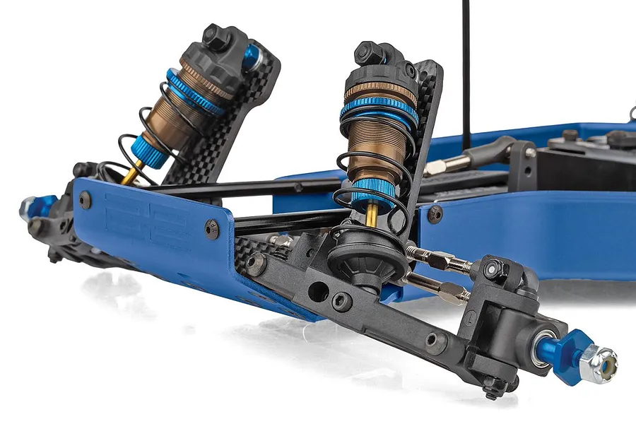 Close-up studio shot of the front suspension, blue aluminum chassis, and threaded shocks of a Team Associated RC car.