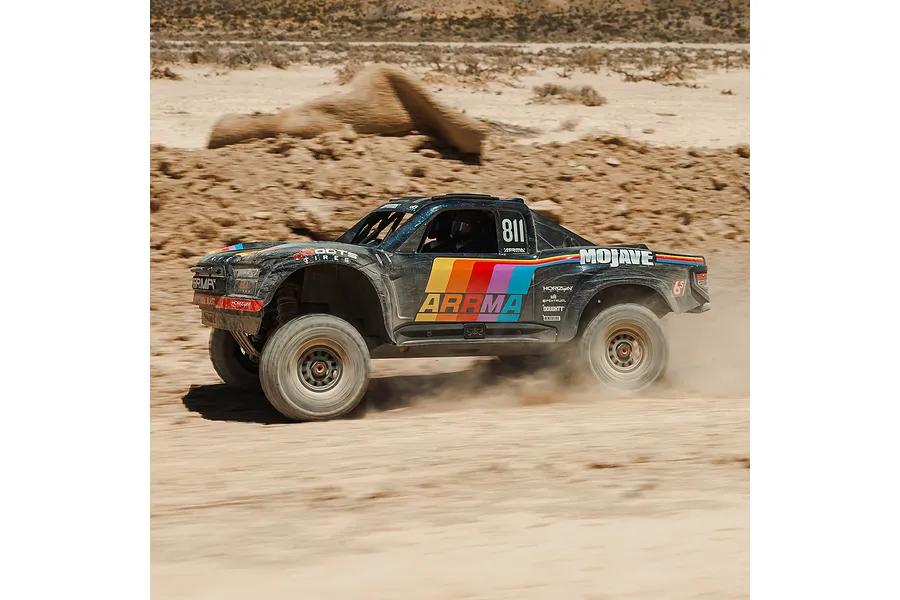 ARRMA MOJAVE 6S RC short course truck driving through a dusty dirt terrain outdoors