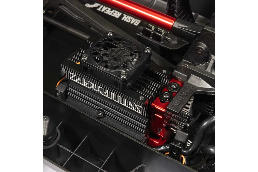 Close-up view of the brushless motor with cooling fan and red anodized aluminum mounts inside an RC short course truck chassis.