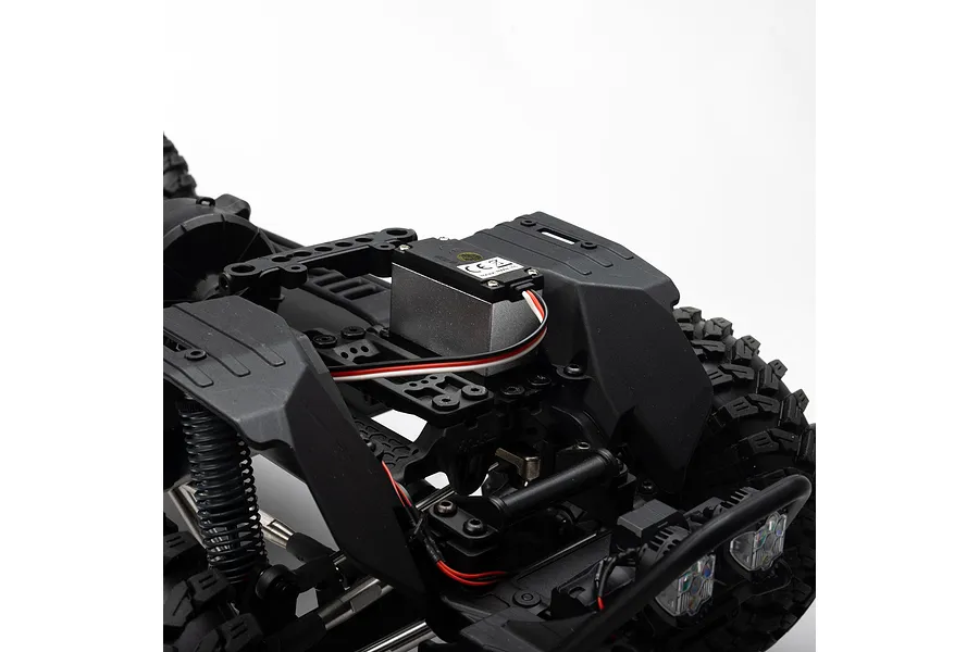 Close-up of the internal chassis and servo of the Axial SCX10 III RC rock crawler against a white background.