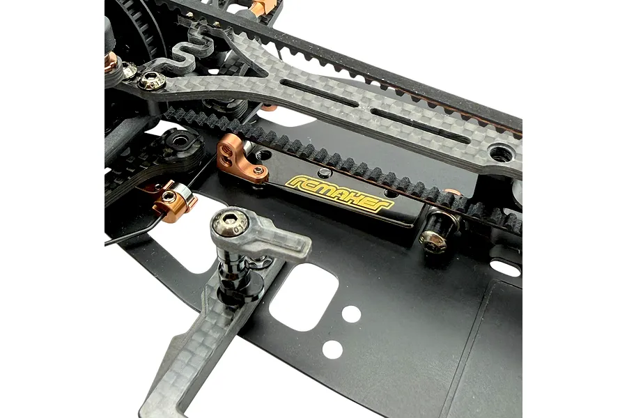Close-up studio view of an RC Maker rear belt tensioner installed on an RC car chassis with carbon fiber parts.