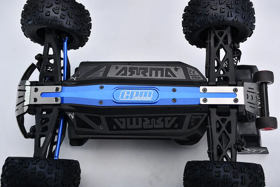 Underside view of an RC car installed with GPM blue aluminium chassis brace and skid plate upgrade parts.