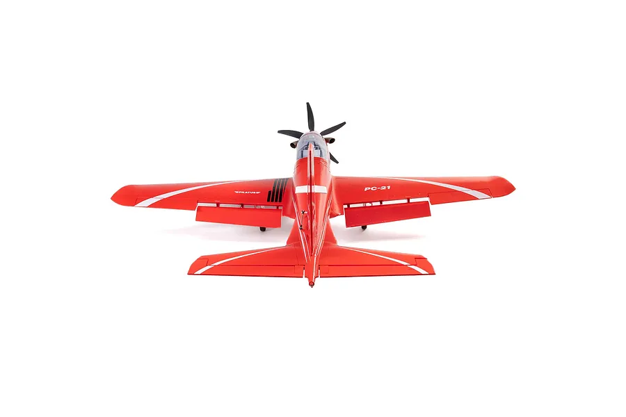 Rear-facing top-down studio shot of the red Pilatus PC-21 RC plane showing deployed flaps and wing details on a white background.