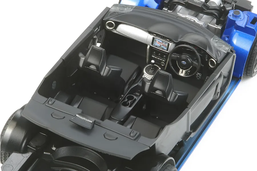 High-angle view of the detailed black interior of a 1/24 scale Tamiya Subaru BRZ model kit, showing seats, dashboard, and steering wheel.