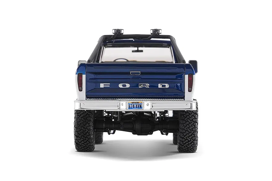 Rear view of the FMS FCX18 II Ford F-100 RC rock crawler in blue and white, showing tailgate details, bumper, and tires against a white background.