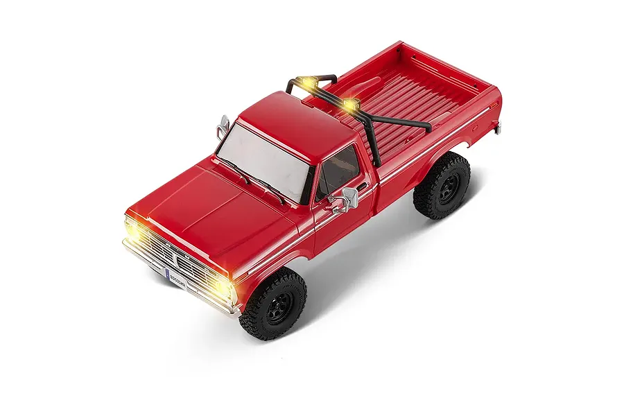 High angle studio shot of the FMS FCX18 II Ford F-100 RC rock crawler in red with illuminated headlights and roll bar lights.