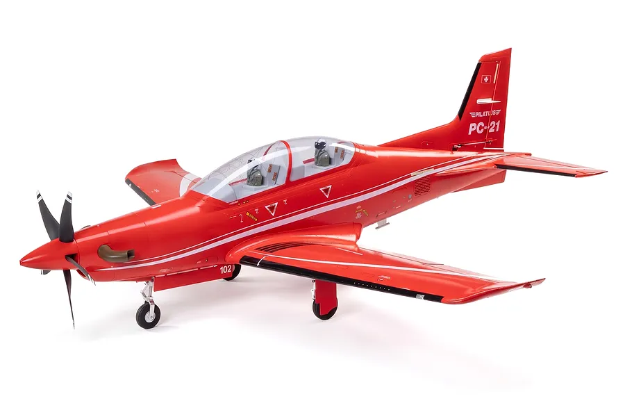 Studio shot of a red E-Flite Pilatus PC-21 RC airplane with white markings, cockpit pilots, and landing gear against a white background.