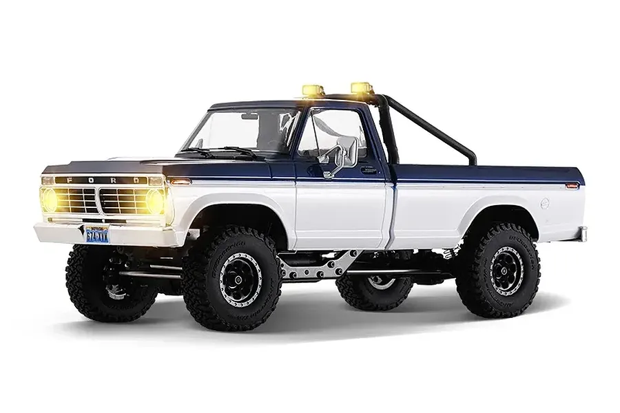 FMS FCX18 II Ford F-100 1/18 scale RC rock crawler truck in blue and white with lit headlights and roll bar.