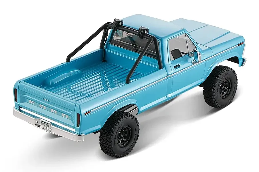 High angle rear studio shot of the cerulean blue FMS FCX18 II Ford F-100 RC rock crawler showing its truck bed and roll bar.