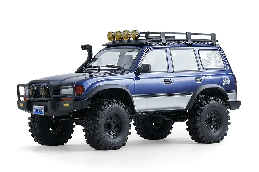 Studio shot of the FMS FCX10 Pro Toyota Land Cruiser LC80 RC rock crawler in blue, featuring a roof rack and bull bar.