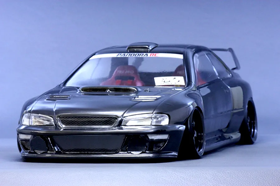 Studio product shot of Pandora RC Subaru Impreza 22B STi 7800 body shell painted dark grey with black wheels and red interior seats.
