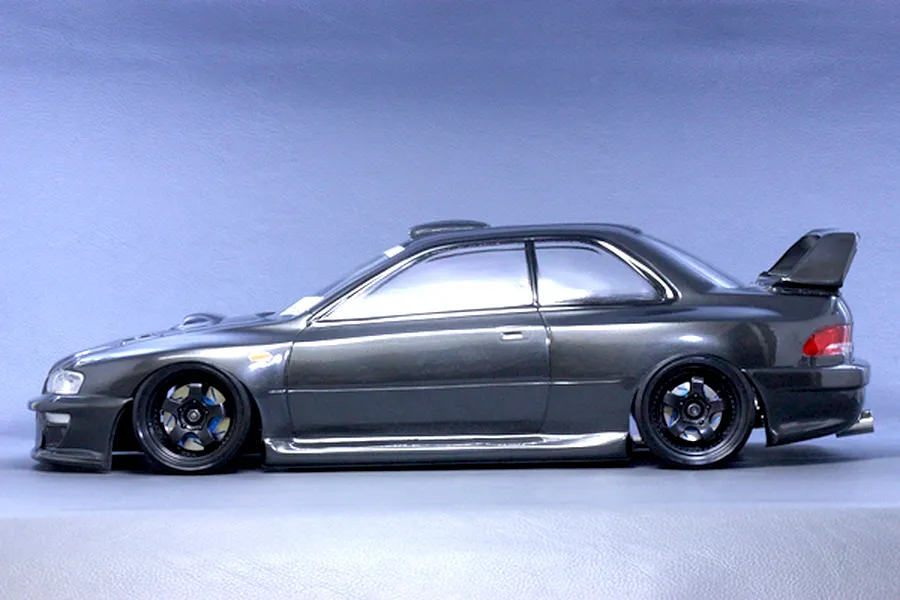 Side profile view of a dark grey RC drift car body styled as a Subaru Impreza 22B STi mounted on a chassis with black wheels.