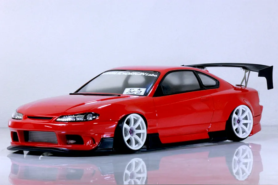 Red RC drift car body styled like an S13 Silvia with white wheels, black aero parts, and a rear wing on a white background.