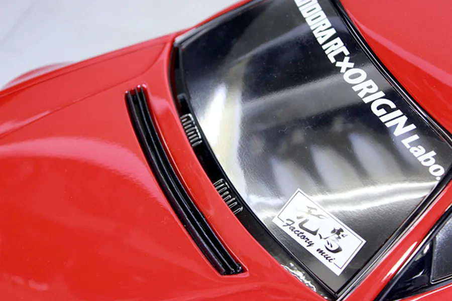 Close-up view of a red RC car body bonnet and windshield with Pandora RC and Origin Labo stickers.