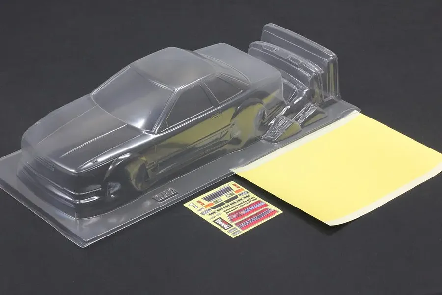 Clear unpainted polycarbonate Pandora RC Toyota Soarer Z20 body shell with included mask sheet and decals on a dark surface.