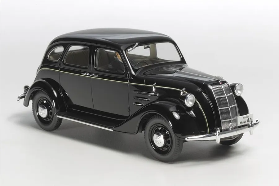 A high-angle studio shot of a black Tamiya 1/24 scale Toyota Toyoda Model AA plastic model car on a white background.
