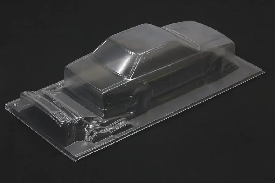 Unpainted clear polycarbonate RC car body shell on a dark background showing the C33 Laurel design.
