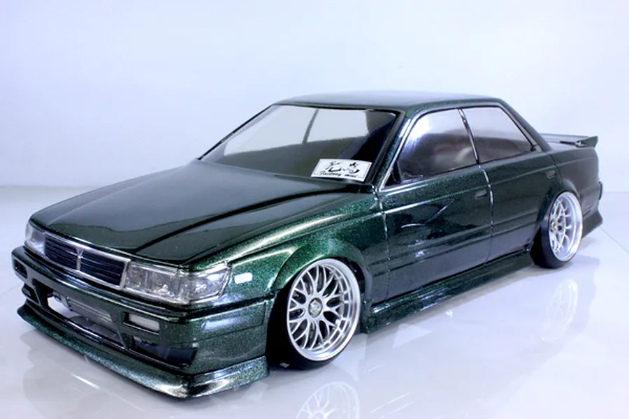 Pandora RC C33 Laurel 7800 drift body shell painted in metallic dark green with custom wheels on a white studio floor.